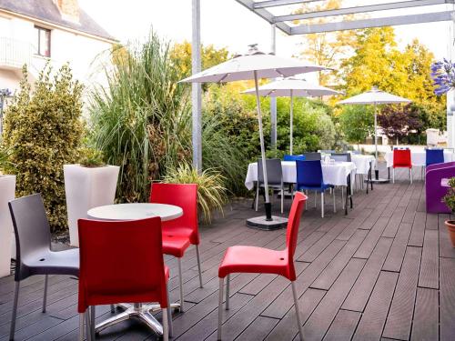 un patio avec des tables, des chaises et des parasols dans l'établissement ibis Styles Rennes St. Gregoire, à Saint-Grégoire