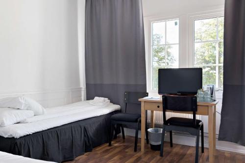 a room with a desk and a bed and a computer at Sure Hotel by Best Western Vilsta Sporthotell in Eskilstuna