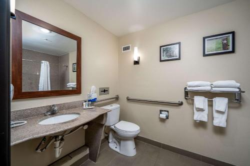 a bathroom with a toilet and a sink and a mirror at Comfort Suites University in Abilene