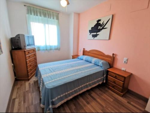Schlafzimmer mit einem Bett, einem TV und einer Kommode in der Unterkunft Apartamento Mar de Oropesa ll in Oropesa del Mar