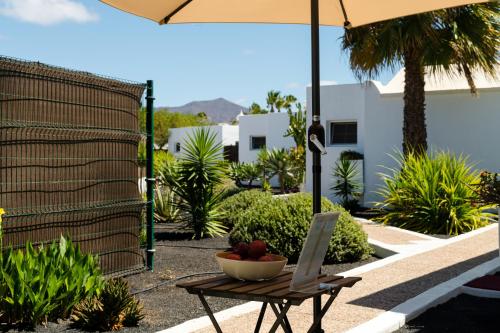 a bowl of fruit sitting on a table under an umbrella at Villas New Lanzasuites in Playa Blanca