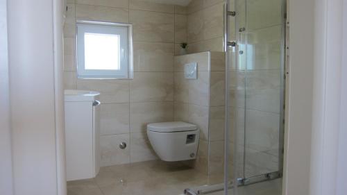 a bathroom with a shower and a toilet and a window at Ogreca in Skradin