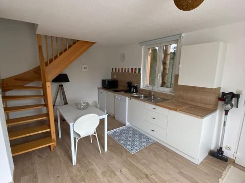 eine Küche mit einem Waschbecken, einem Tisch und einer Treppe in der Unterkunft Logement de charme au coeur de la nature in Osenbach