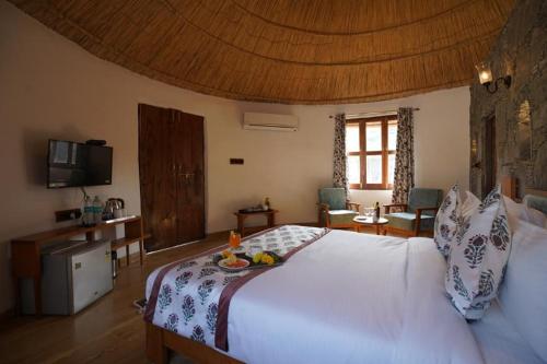 a bedroom with a white bed with a tray of fruit on it at Turban Nature Wilderness , Kumbhalgarh in Kumbhalgarh