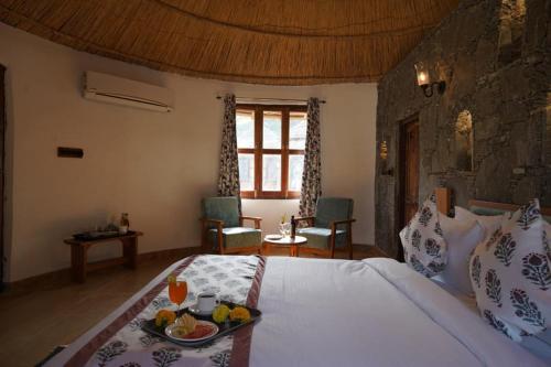 a bedroom with a bed with a tray of fruit on it at Turban Nature Wilderness , Kumbhalgarh in Kumbhalgarh