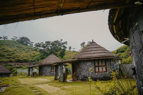 two small huts with thatched roofs in a field at Turban Nature Wilderness , Kumbhalgarh in Kumbhalgarh