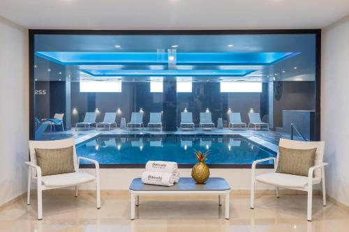 a pool in a room with chairs and a table at Barceló Aracena & Spa in Aracena
