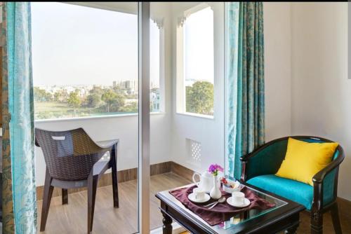 a living room with a chair and a table and a window at Vasant Vilas in Udaipur