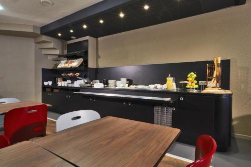 a restaurant with a counter and tables and chairs at Campanile Paris Ouest - Porte de Champerret Levallois in Levallois-Perret