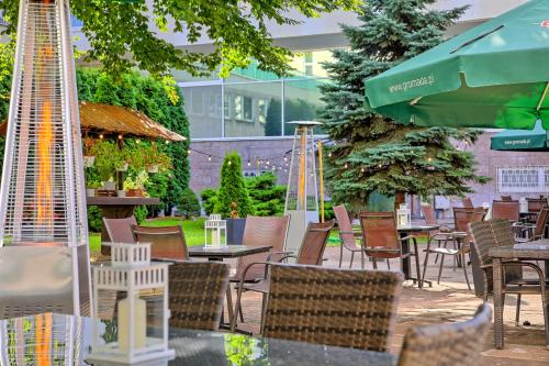 patio z krzesłami, stołami i parasolem w obiekcie Hotel Gromada Warszawa Centrum w Warszawie