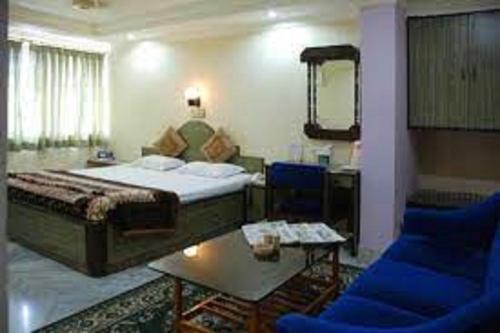 a hotel room with a bed and two blue chairs at Hotel Sukhakarta, Nagpur in Nagpur