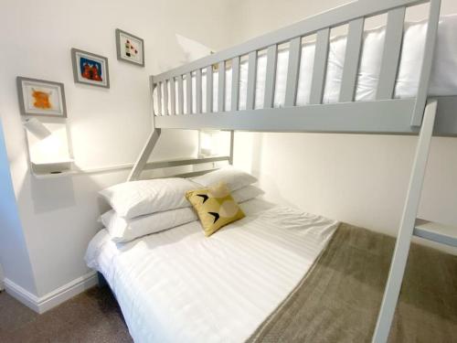 białe łóżko z żółtymi poduszkami w pokoju w obiekcie The Wee Bunk House - Innerleithen w mieście Innerleithen