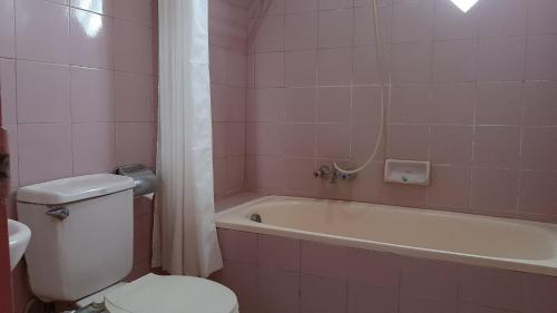 a pink bathroom with a toilet and a bath tub at Hotel Parewisata in Parepare