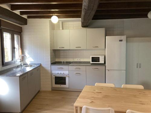 cocina con electrodomésticos blancos y mesa de madera en Monforte de la Sierra - Acogedora y cálida vivienda 