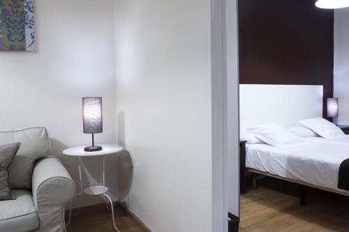 a bedroom with a bed and a chair and a lamp at THC Gran Via Hostel in Madrid