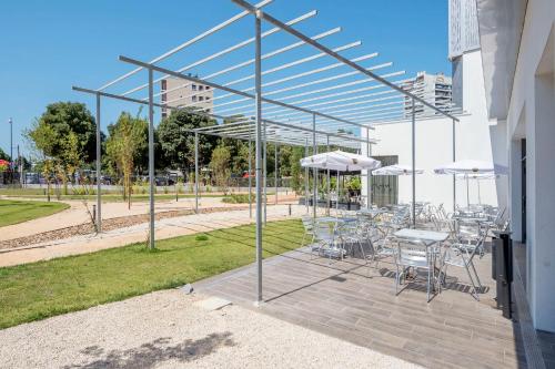 a patio with tables and chairs and umbrellas at B&B HOTEL Marseille Prado Vélodrome in Marseille