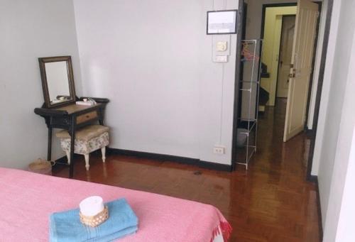 a room with a pink bed and a table and a mirror at Wayside Guesthouse in Chiang Mai