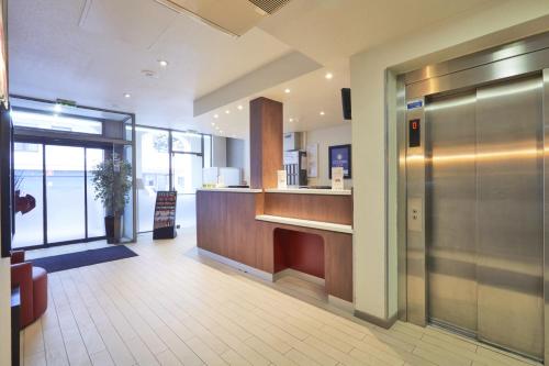 an office lobby with a reception desk and a sliding door at Campanile Paris Ouest - Porte de Champerret Levallois in Levallois-Perret