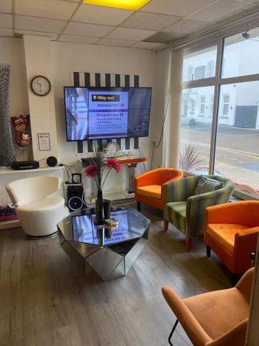 salon z telewizorem, stołem i krzesłami w obiekcie The Cosy Nook w Blackpool
