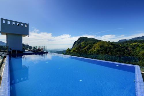 a swimming pool with blue water and mountains in the background at Morning Dew Boutique Hotel Ella in Ella
