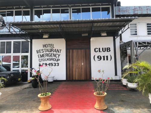 una puerta delantera de un edificio con dos macetas en Hotel Bar Restaurant Emergency 911 STO LK GROUP, en Paramaribo