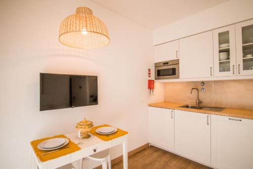 a kitchen with white cabinets and a table with plates on it at 188 Apartments - Buganvília - pool and balcony in Cascais
