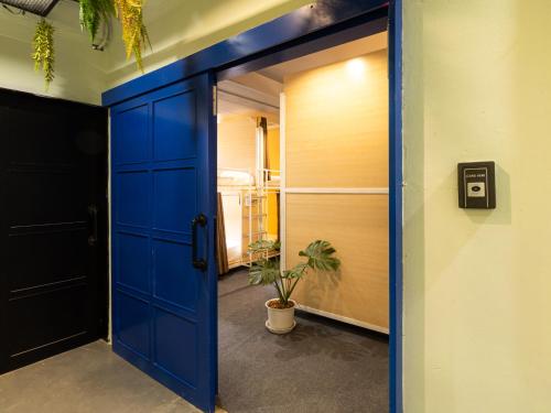 a blue door leading into a room with a potted plant at Khao San Social Capsule Hostel in Bangkok