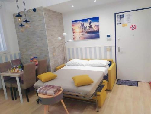 Un dormitorio con una cama con almohadas amarillas y una mesa. en San Siro Dream Home -Apartment with garage-Milano en Milán