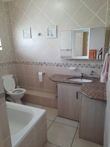 a bathroom with a toilet and a sink and a tub at Uvongo square Unit 24 in Uvongo Beach