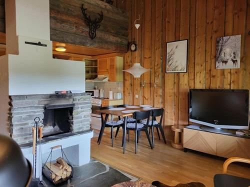 ein Wohnzimmer mit einem Tisch, einem TV und einem Kamin in der Unterkunft Chill Cave - logwood cottage in Ruka