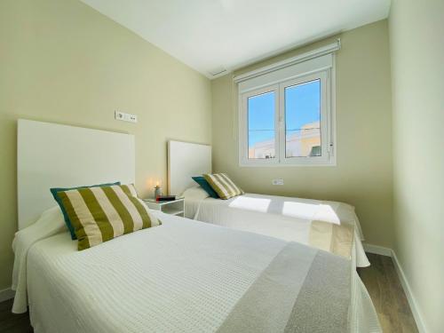 2 weiße Betten in einem Zimmer mit Fenster in der Unterkunft Summerlandrota Argüelles 4 in Rota