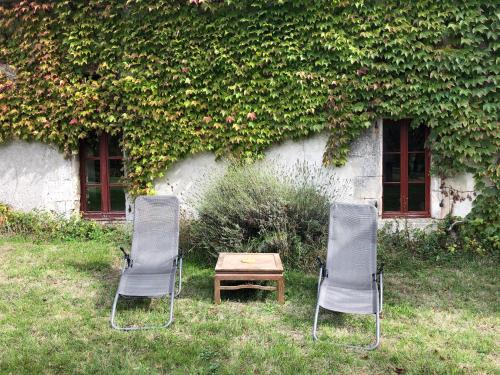 two chairs and a table in front of a building at Gîte de L’Edelinie in Nanteuil-de-Bourzac