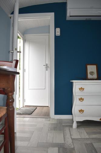 a blue room with a white dresser and a door at Pipowagen ''Slapen by Co'' in Leerdam