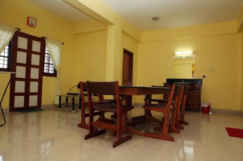 a dining room with a wooden table and chairs at Redrose Service Apartment in Kannur