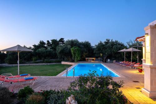 a pool with chairs and umbrellas in a yard at Villa Luni in  Episkopi (Chania)