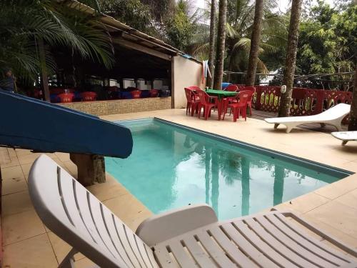a swimming pool with chairs and a table and a table and chairs at Pousada Refúgio Do Capitão in Praia de Araçatiba