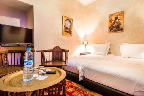 una habitación de hotel con 2 camas y una mesa con una botella de agua en Riad Boustane, en Marrakech