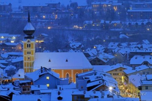 a city covered in snow at night with a clock tower at Sunrise Apartment in Schladming