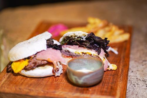 a sandwich on a wooden cutting board with a sauce at Terra Firma Hotel Boutique in Villa Carlos Paz