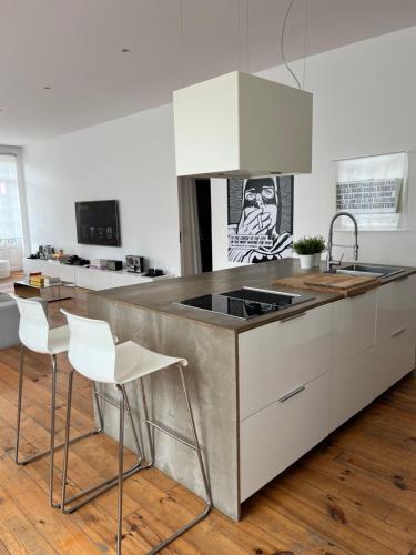 a kitchen with a sink and a counter with white chairs at City center boutique apartment in Funchal