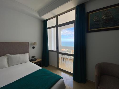 a bedroom with a bed and a large window at Hotel Azur in Casablanca