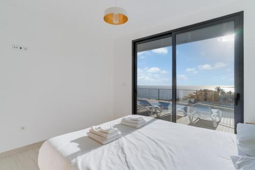 a white bedroom with a view of the ocean at Casa Mozart II in Estreito da Calheta
