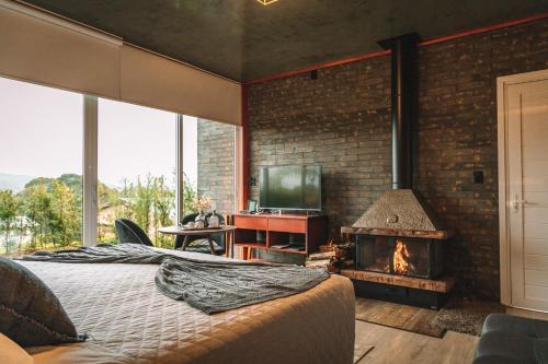 a bedroom with a brick wall and a fireplace at Pousada Cantelli in Bento Gonçalves