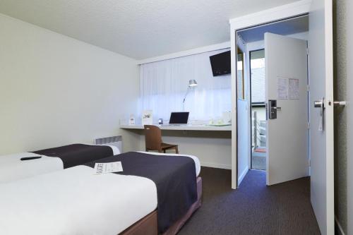 a hotel room with two beds and a desk with a laptop at Campanile Lille Sud - CHR in Lille
