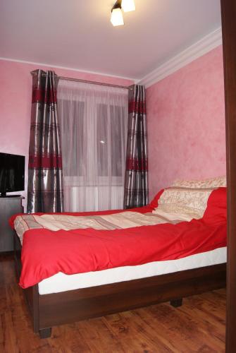 a bedroom with a bed with red sheets and a window at Living Room in Tarnów