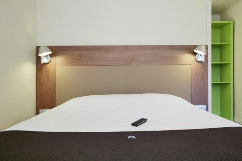 a bedroom with a white bed with a remote control on it at Campanile Lille Sud - CHR in Lille