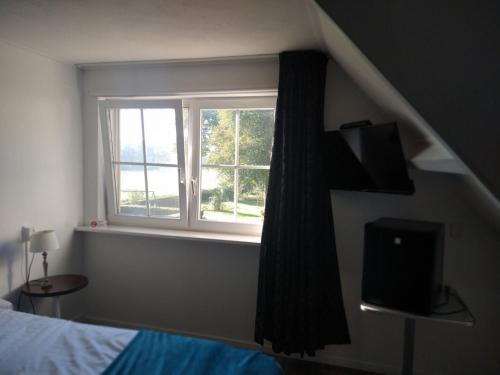 een slaapkamer met een raam, een bed en een televisie bij B&B-Hotel de Joremeinshoeve in Kaatsheuvel