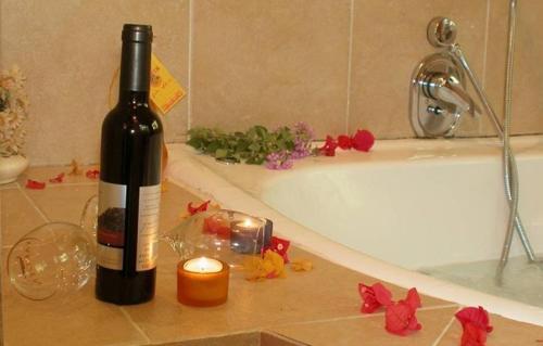 a bottle of wine and a candle next to a bath tub at Pundak guesthouse in Moshav Ramot