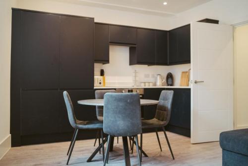 Apartment 4 2 bedroom, sleeps x 6 في يورك: مطبخ به دواليب سوداء وطاولة وكراسي
