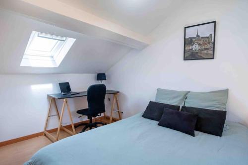 a bedroom with a bed and a desk with a laptop at Charmante Amiénoise 2 chambres in Amiens